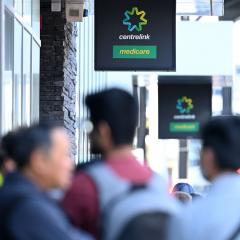 An image of the Centrelink signs outside of a building with blurred image of people below.